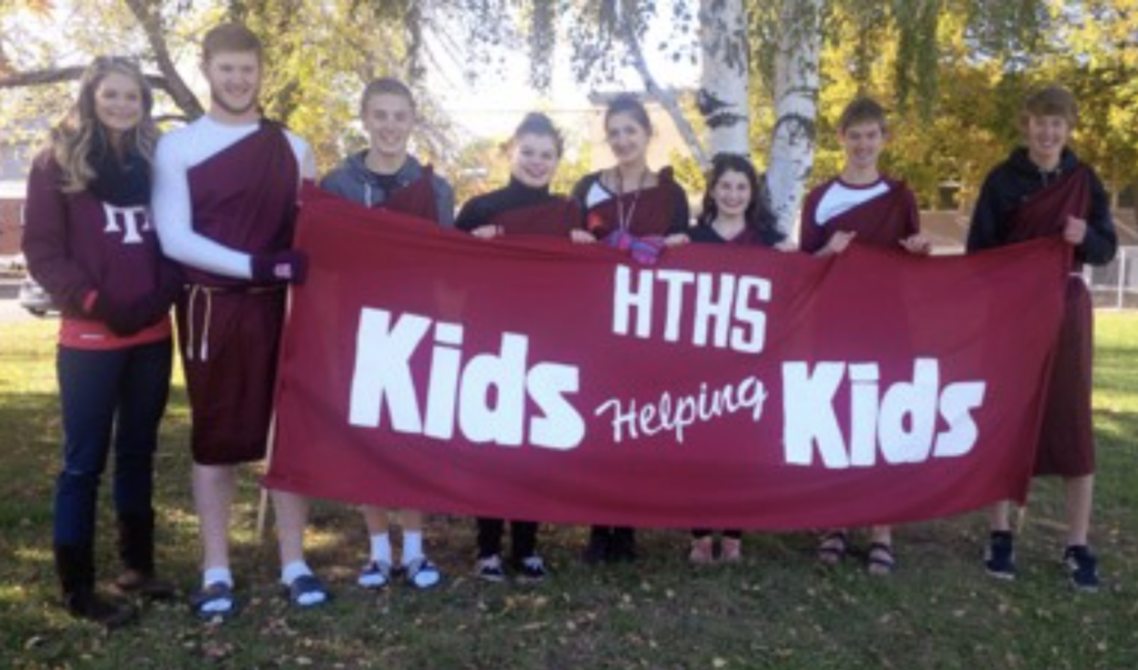 Students from Harrison Trimble High School stand with sign that says HTHS Kids Helping Kids