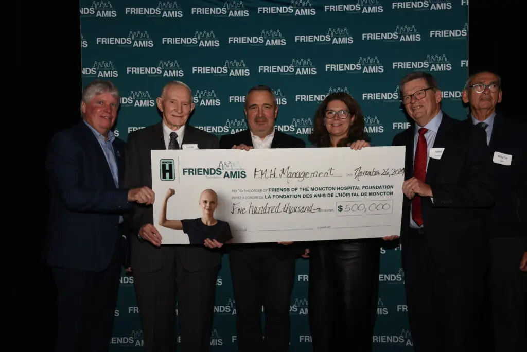 Group of people holding up large cheque at cheque presentation.